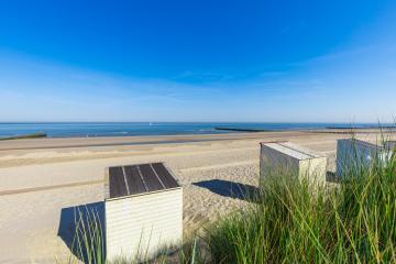 Een blauwe hemel boven de strandhuisjes